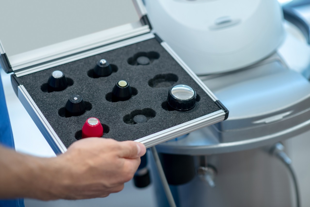 Ultrasound treatment. Close-up of male hands holding box with ultrasound machine changable heads