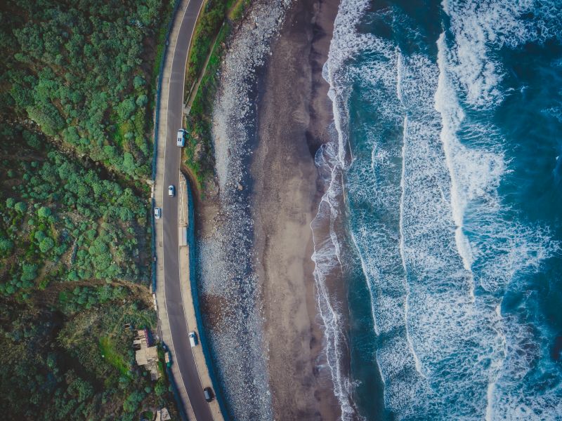 cars driving on road next to ocean