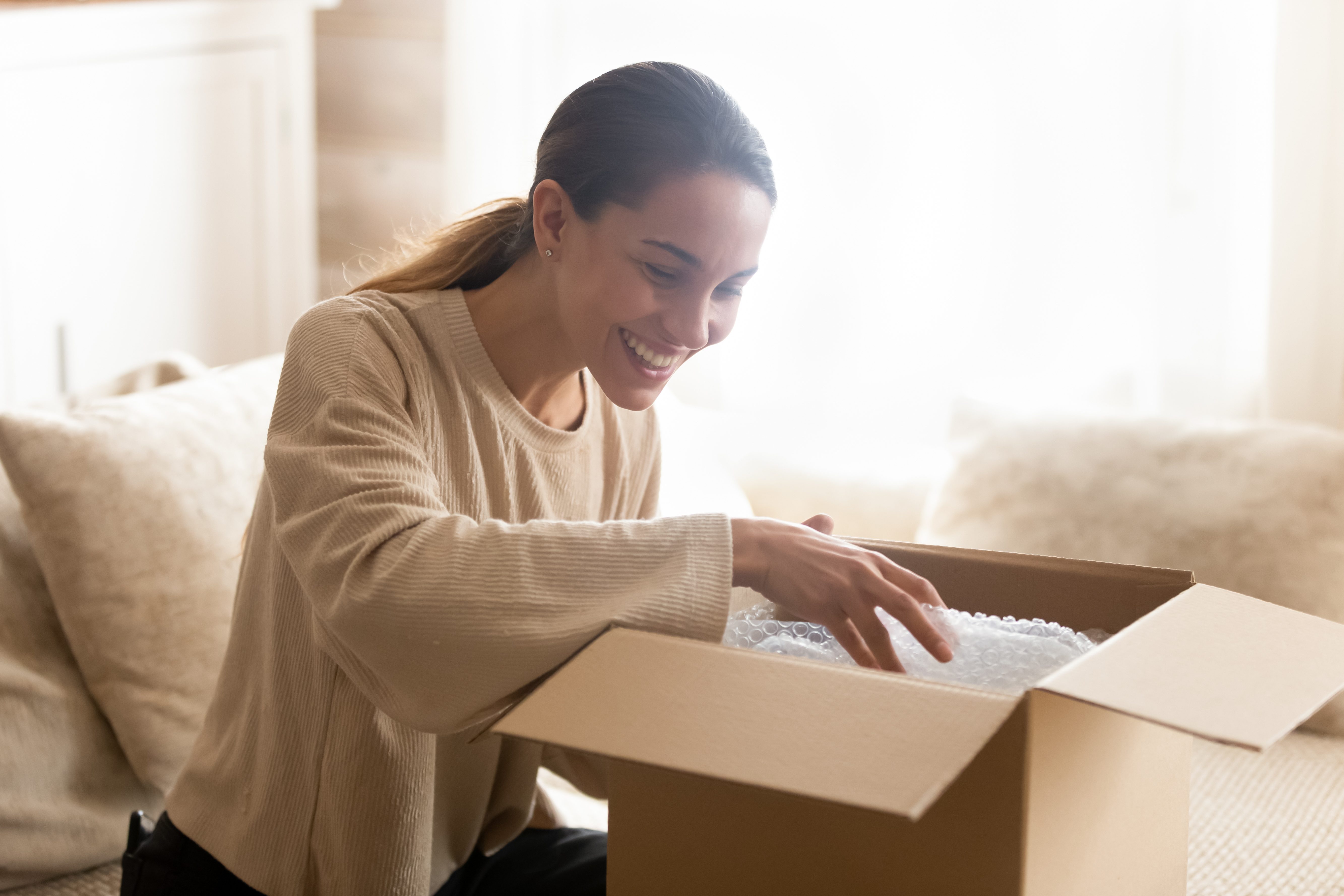 Frau öffnet Verpackung mit Luftpolsterfolie